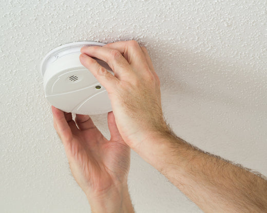 A person installing a smoke detector.