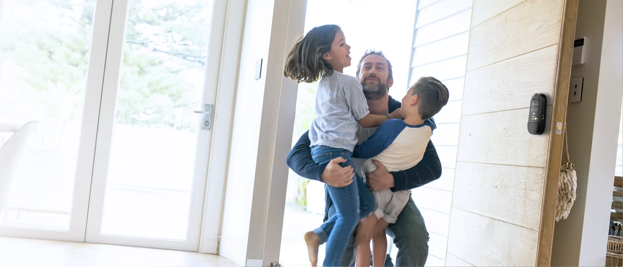 Man lifting a child in a home setting with a Lockly Smart Lock doorbell 
